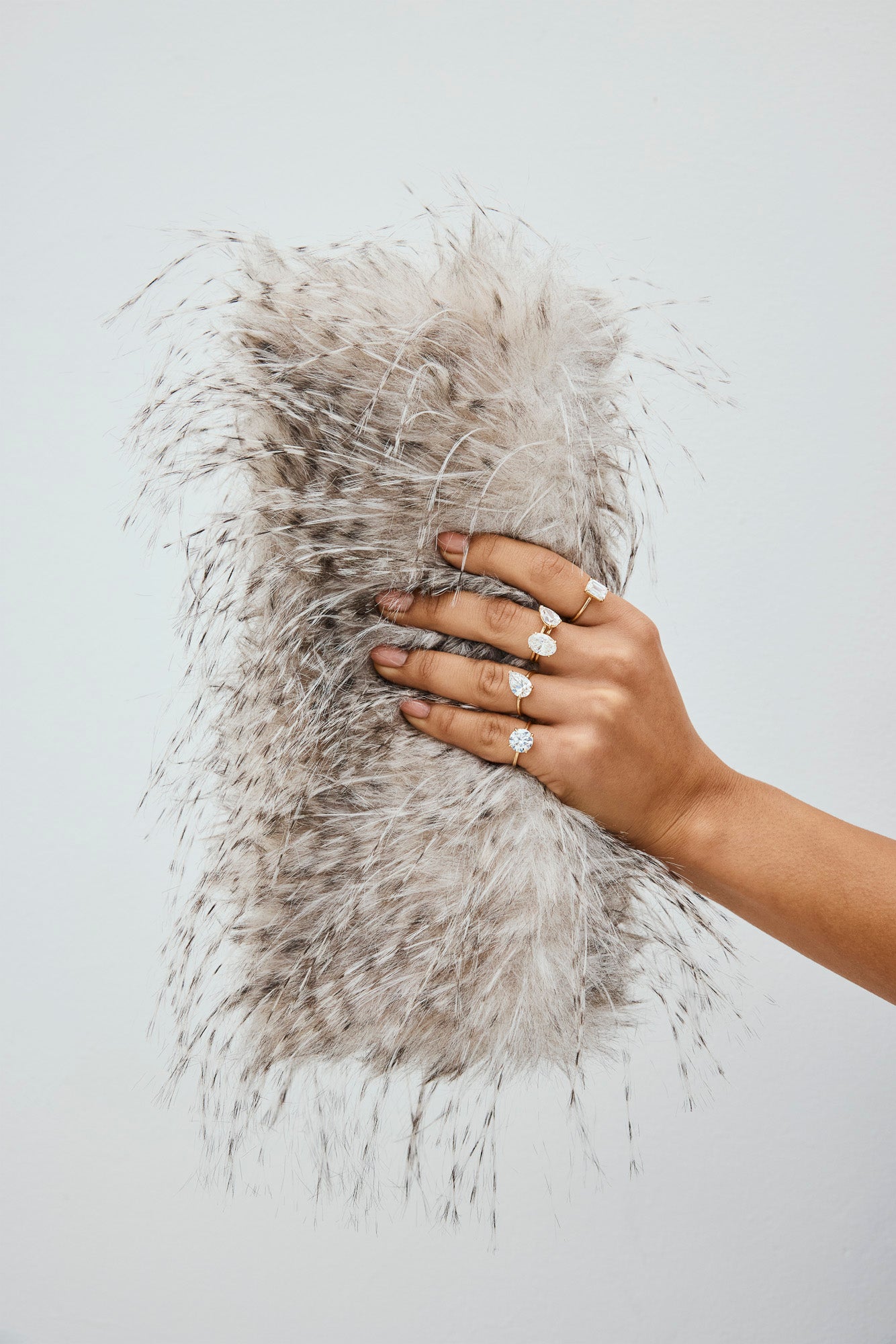 Hand wearing lab-grown diamond rings holding a textured clutch