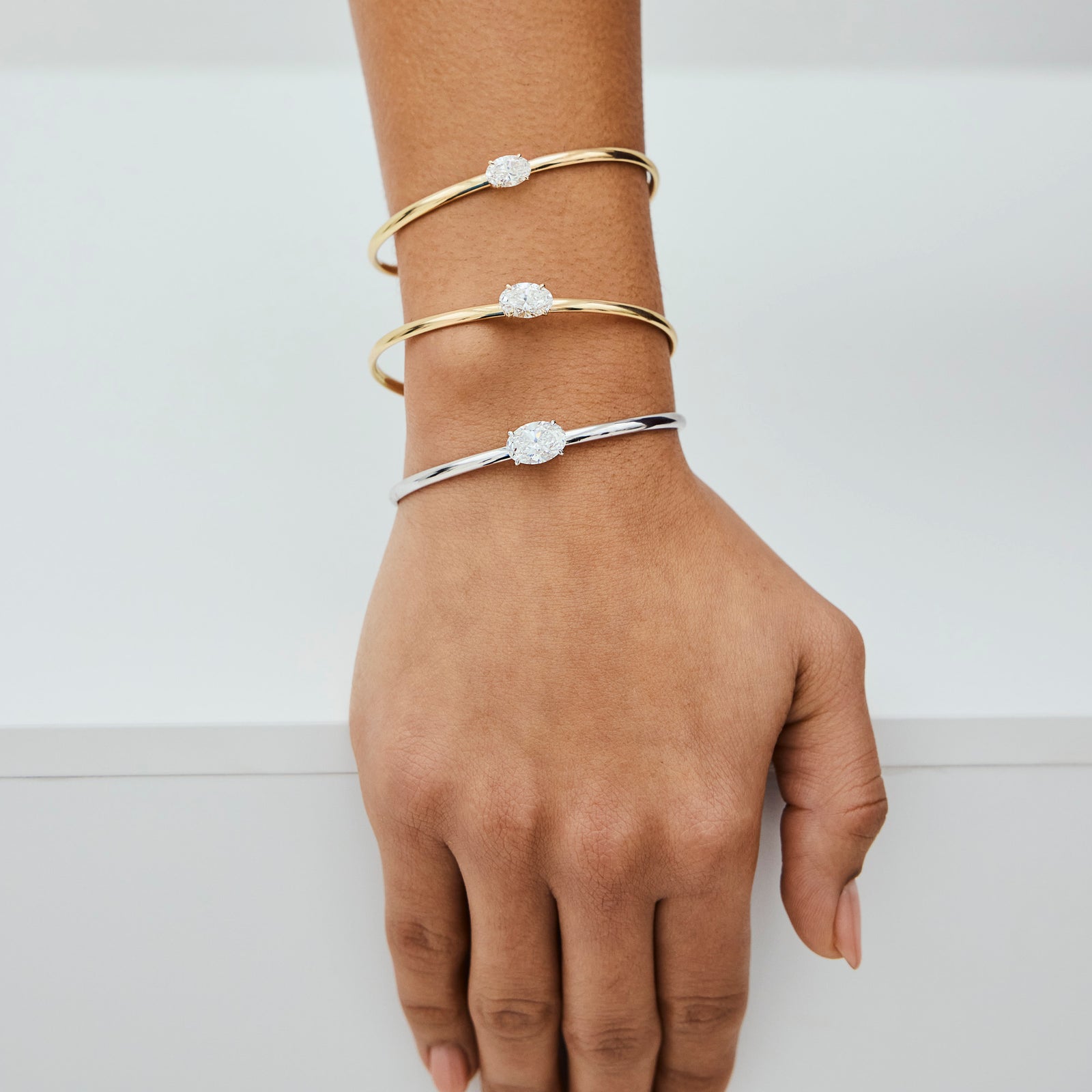 Three lab-grown diamond bracelets on a hand in yellow and white gold